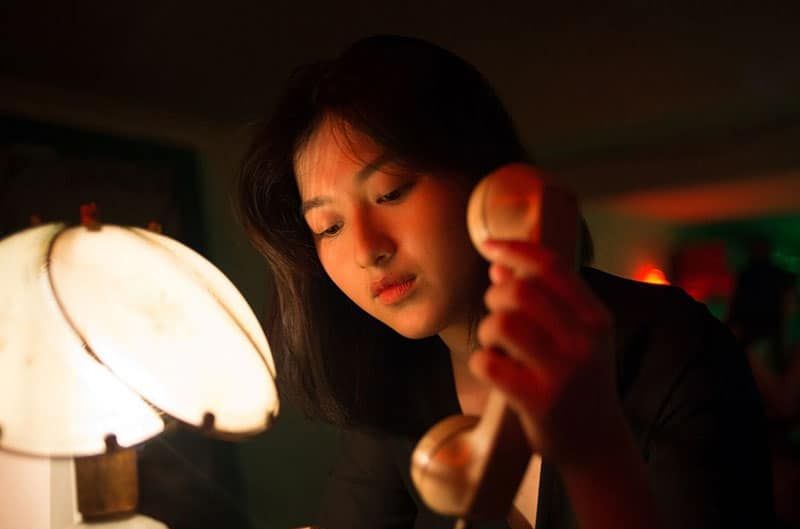 donna che tiene un telefono vicino a una lampada da tavolo
