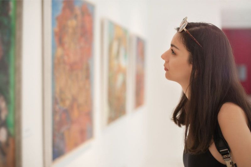 wanita mengunjungi galeri seni dengan seni di dinding