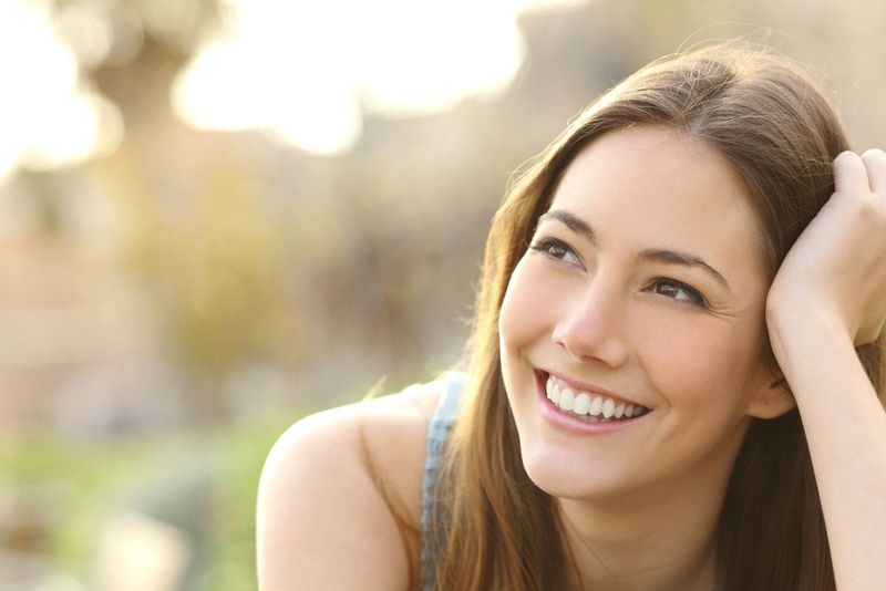 wanita tersenyum berpikir dan tangannya menopang kepalanya dalam fokus