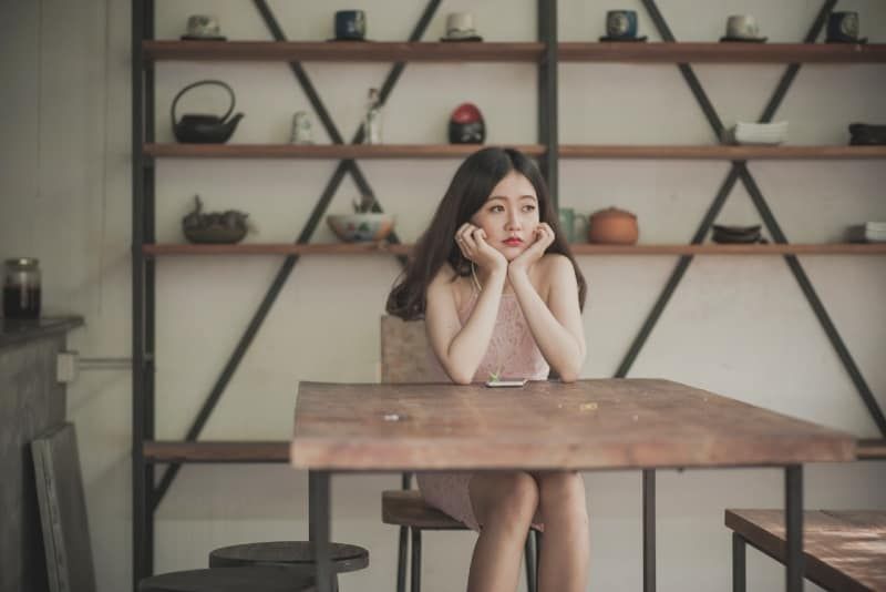 wanita duduk di meja dan mendengarkan musik
