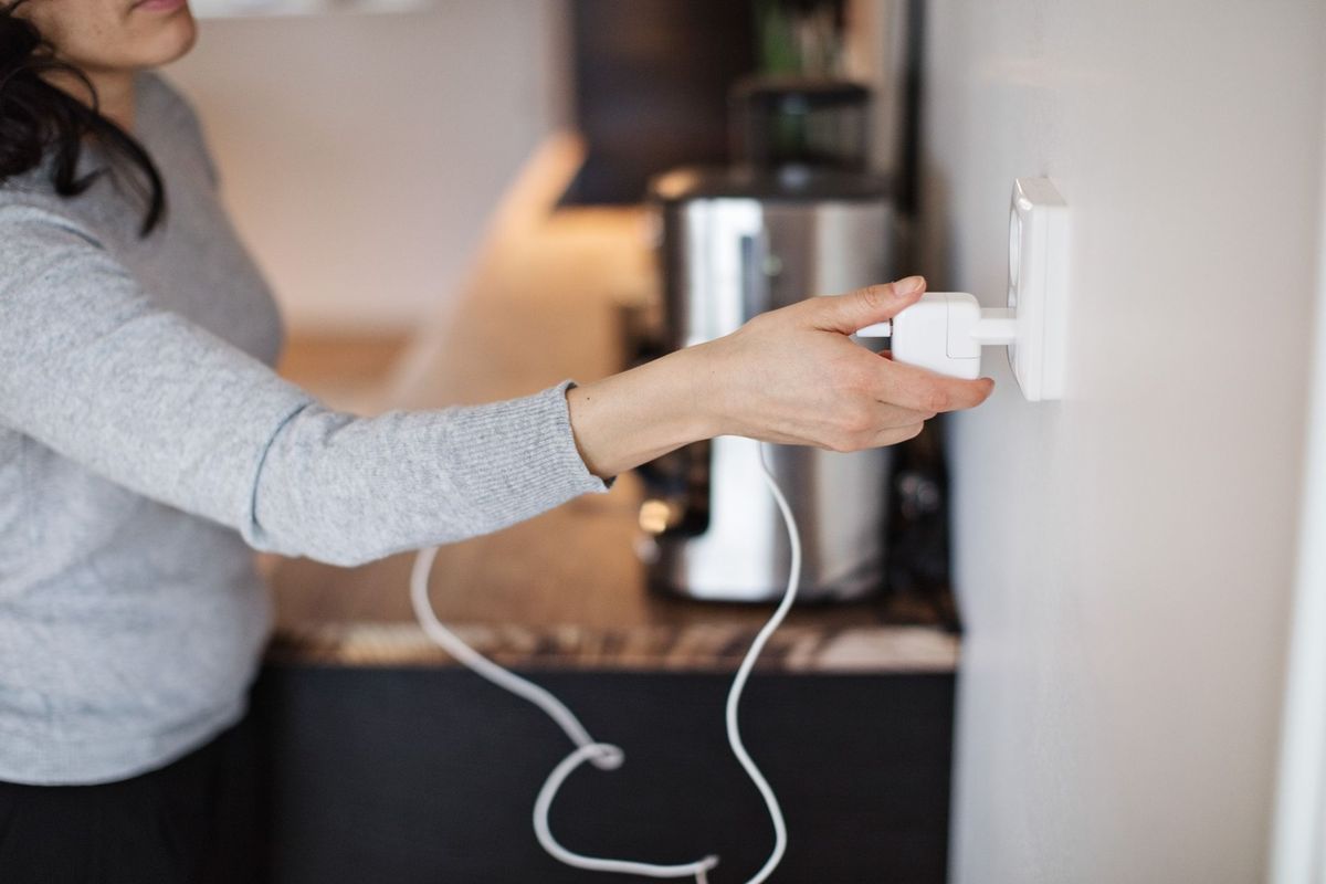 Người phụ nữ cắm sạc điện thoại di động trên tường ở nhà