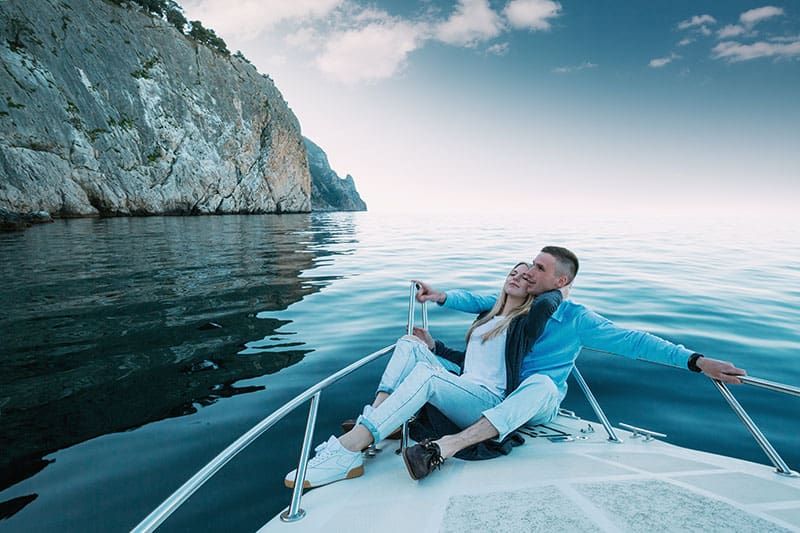 ヨットでリラックスした若いカップル。幸せな裕福な男性とプライベートボートでの女性が海の旅をしています