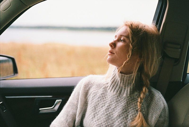 Vrouw met witte gebreide trui in de auto