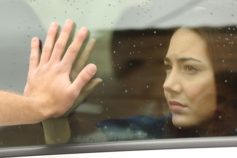 Vrouw achter autoraam terwijl een man er met een hand op leunt