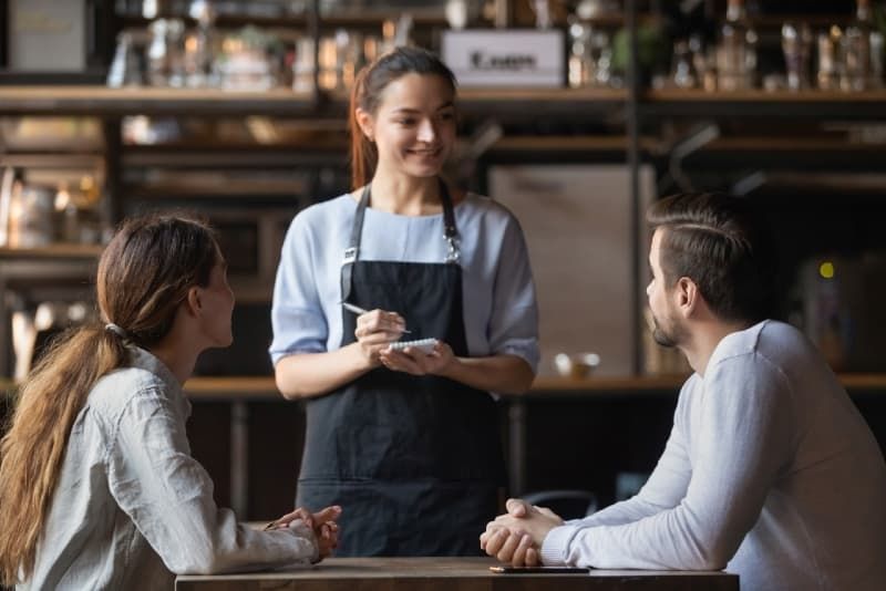 bărbat vorbind cu barista în timp ce stă la masă