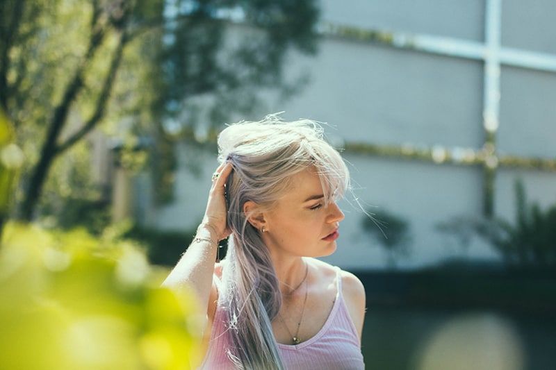 vrouw die haar haar aanraakt terwijl ze in de buurt van een gebouw staat