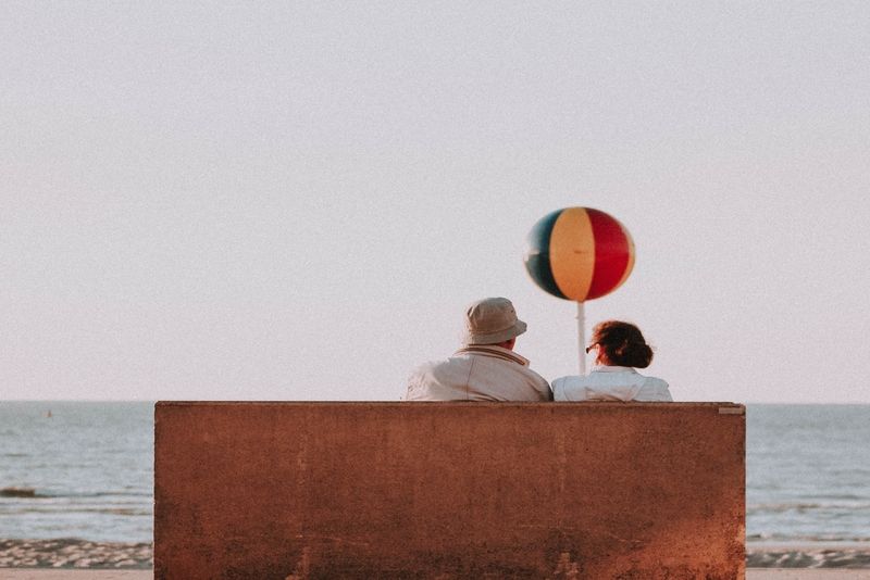 mann und frau unterhalten sich, während sie in der nähe des meeres sitzen