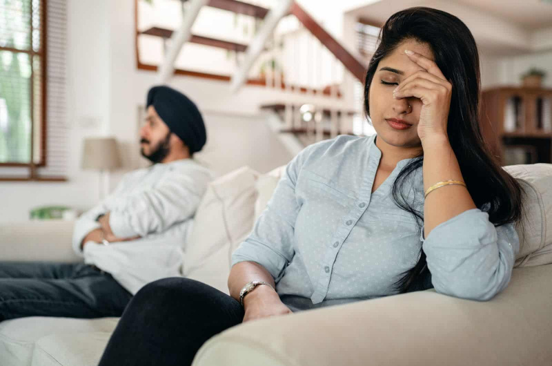 istri dan suami duduk di sofa saling berhadapan sementara istri memikirkan kembali perceraian