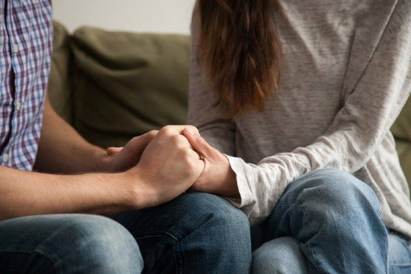 magkahawak kamay ang lalaki at babae habang nakaupo sa sofa