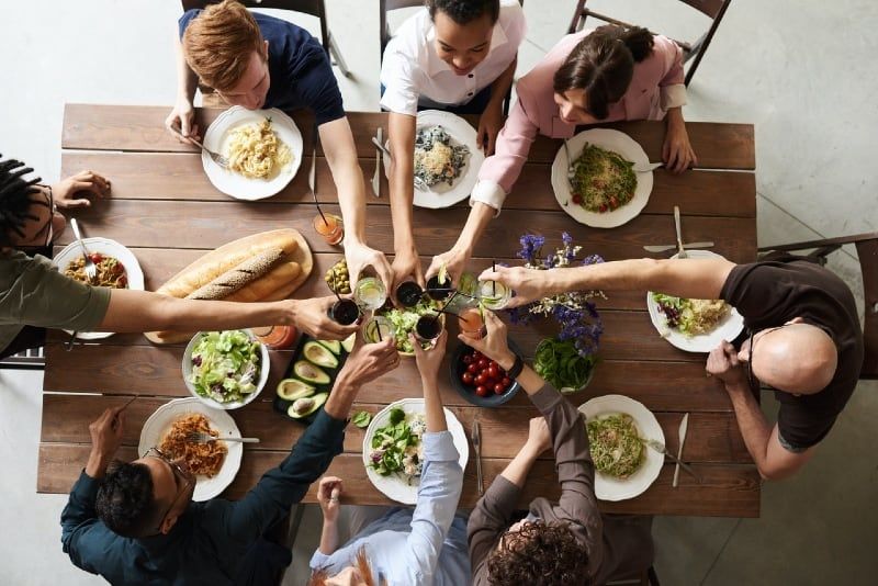 grupo ng mga taong gumagawa ng toast habang nakaupo sa mesa