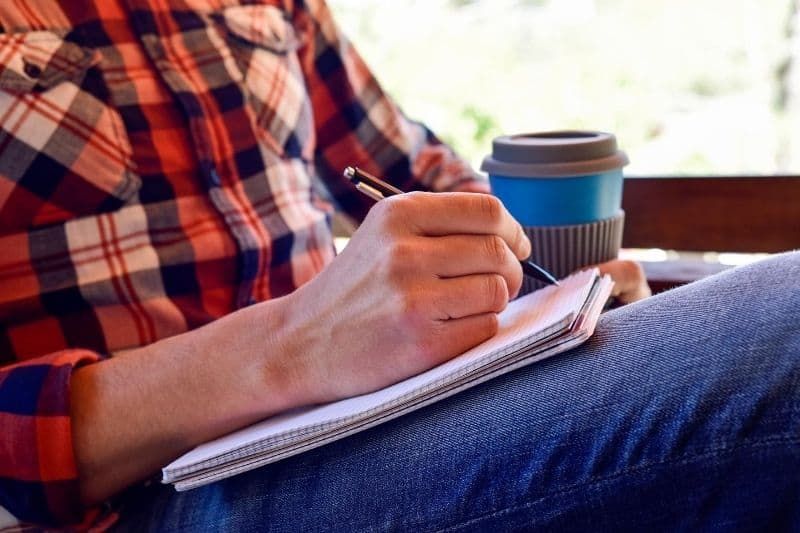 رجل يكتب قصيدة على دفتر مع القهوة بجانبه