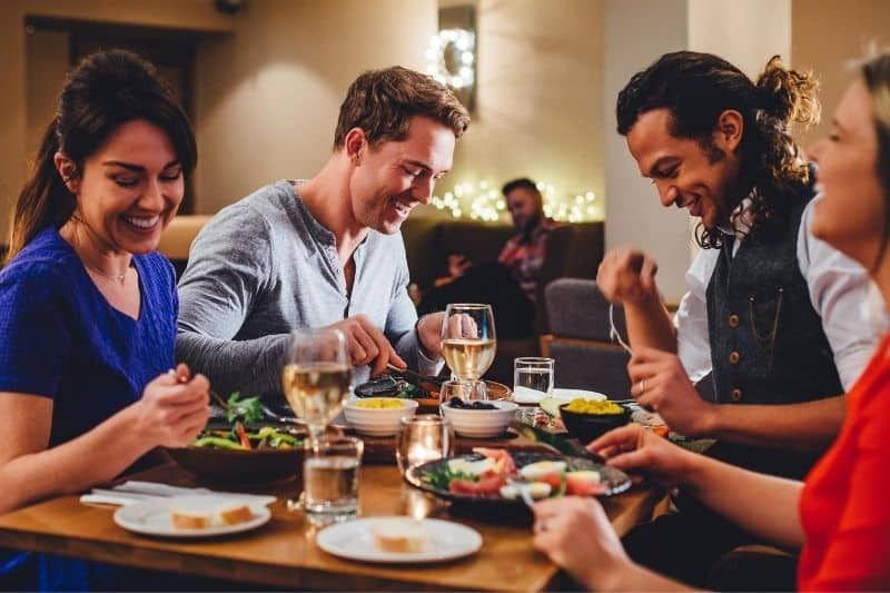 تناول الطعام مع موعد مزدوج يستمتع به 4 أصدقاء على الطعام والضحك الجيد