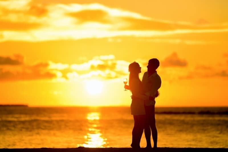 زوجين أثناء غروب الشمس تعانق مع كأس من النبيذ