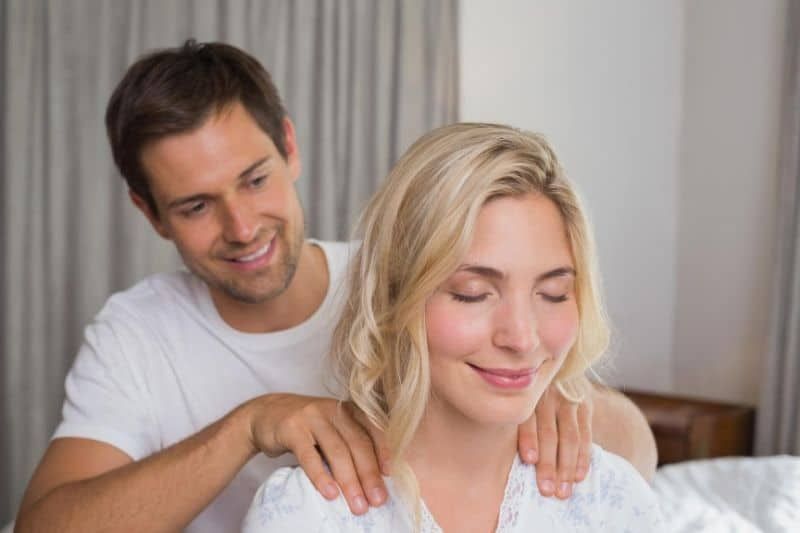 الرجل يقوم بتدليك ظهر المرأة داخل المنزل