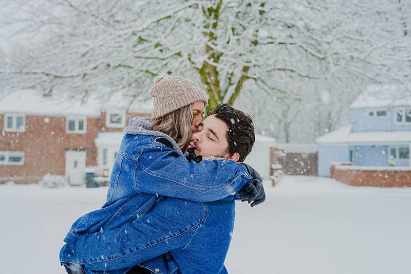 Home que sosté la dona als seus braços sobre la neu