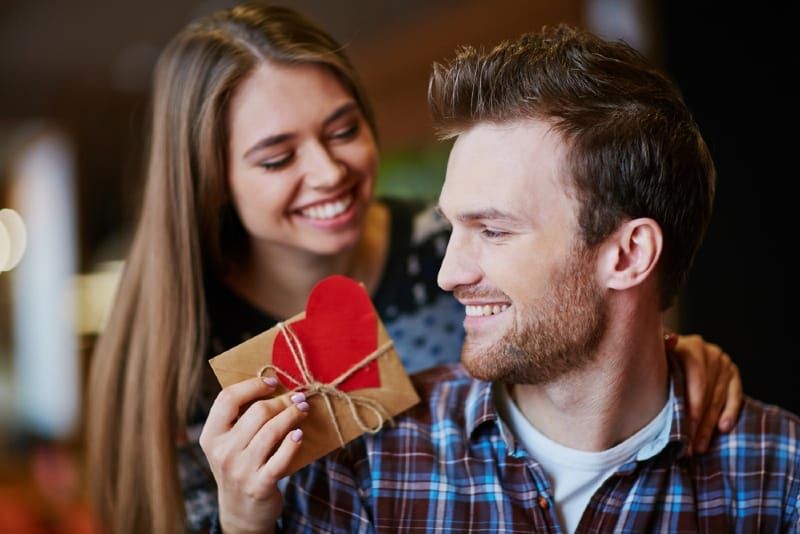 smilende kvinde giver gave til mand