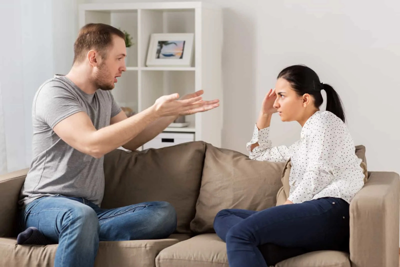   một người đàn ông cãi nhau với một người phụ nữ khi ngồi trên chiếc ghế dài