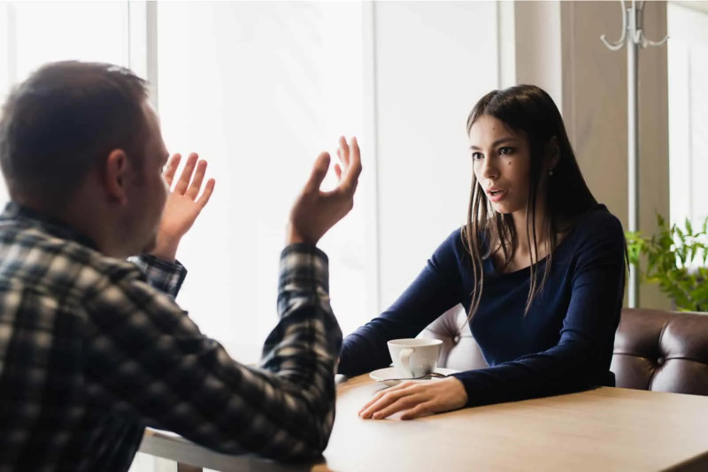   một người đàn ông và một người phụ nữ ngồi vào bàn và tranh luận