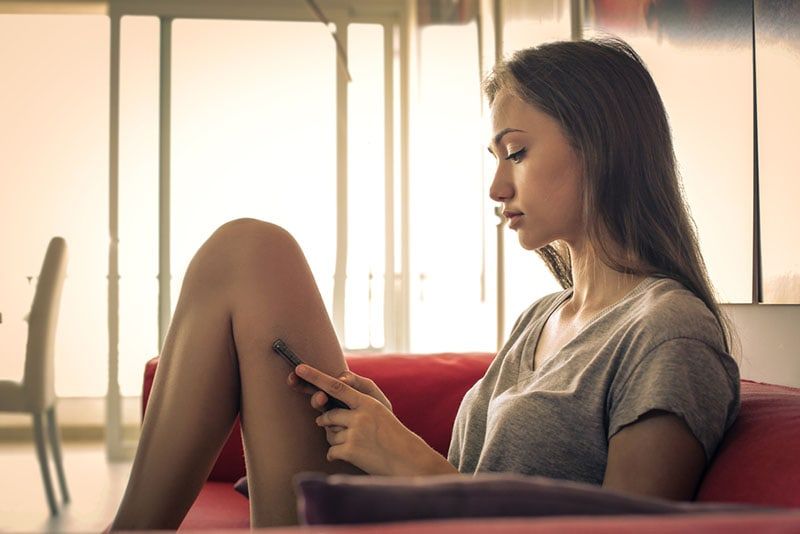người phụ nữ buồn ngồi trên ghế và nhắn tin