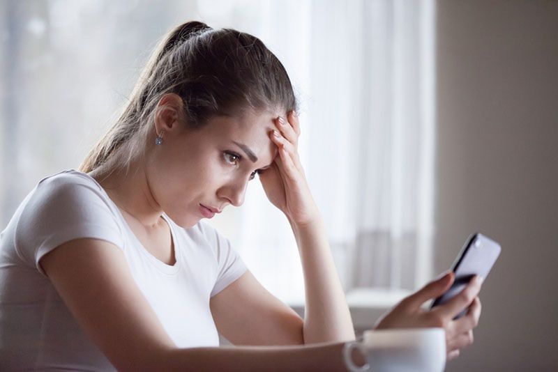 người phụ nữ trẻ lo lắng nhìn vào điện thoại