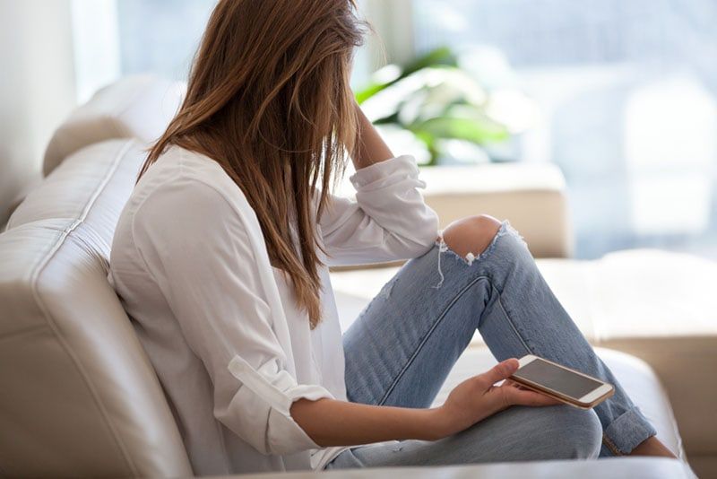 người phụ nữ buồn bã cầm điện thoại