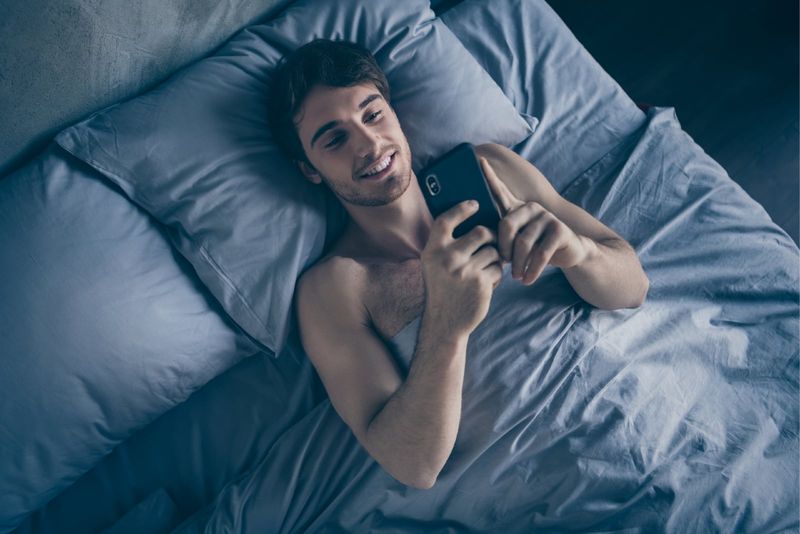 homem feliz deitado na cama enquanto estiver usando smartphone