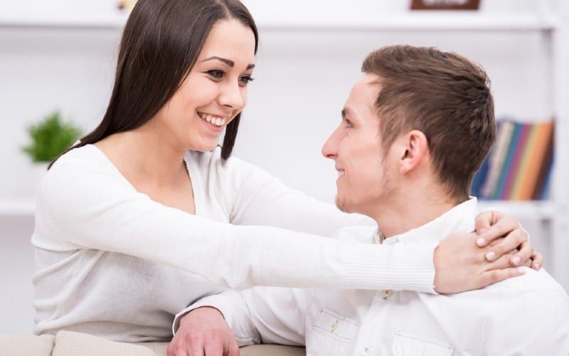 Mulher feliz no vestido branco segurando o homem sorridente no top branco