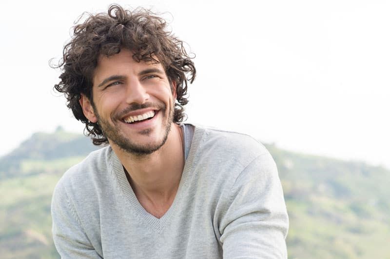 homem de cabelo cacheado sorrindo