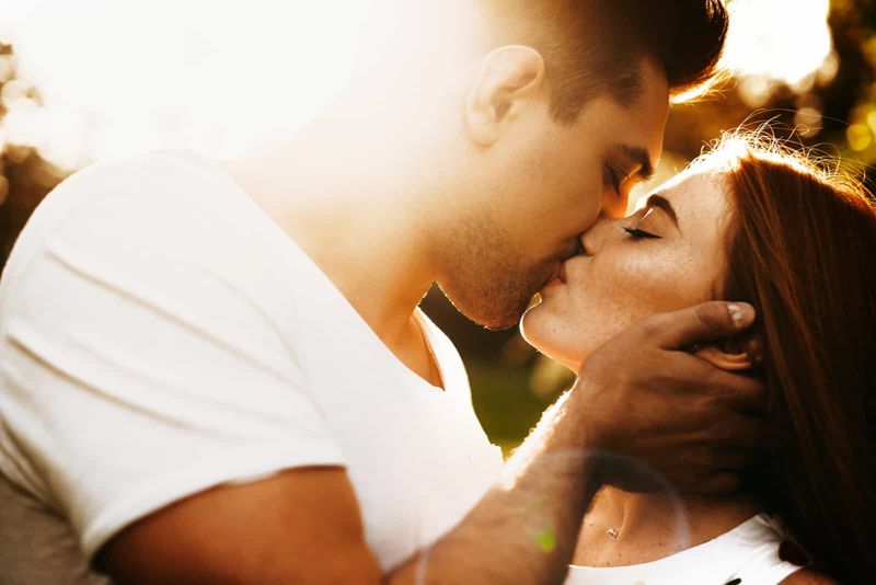 một người đàn ông ôm cổ một người phụ nữ và hôn cô ấy