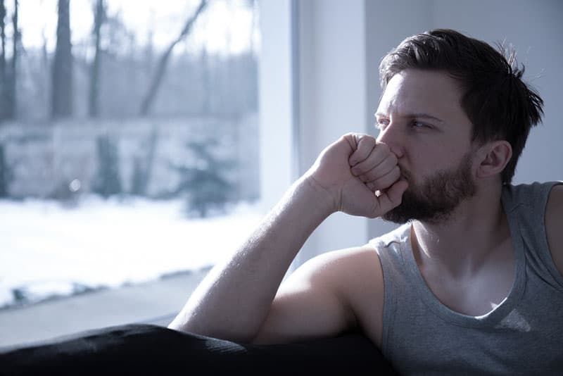 Trauriger Mann, der durch das Fenster schaut
