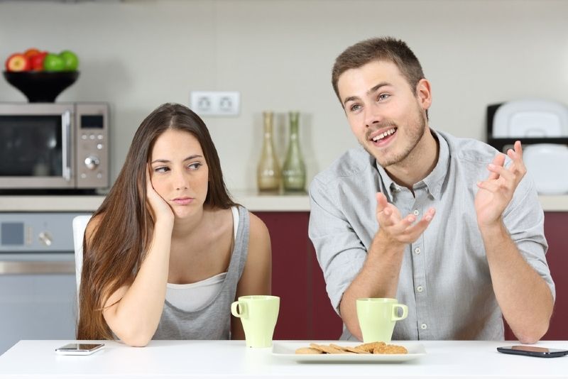 homem feliz falando enquanto está sentado perto de mulher