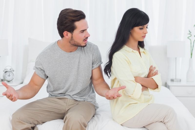 homem de camiseta cinza falando com mulher interior