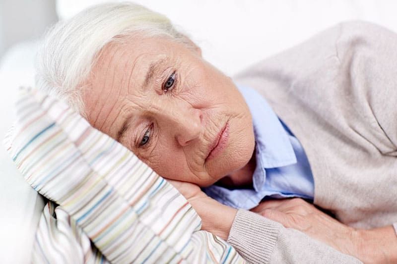 dona gran trista estirada al coixí a casa