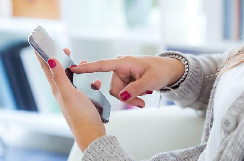 la mà de la dona tocant el telèfon intel·ligent