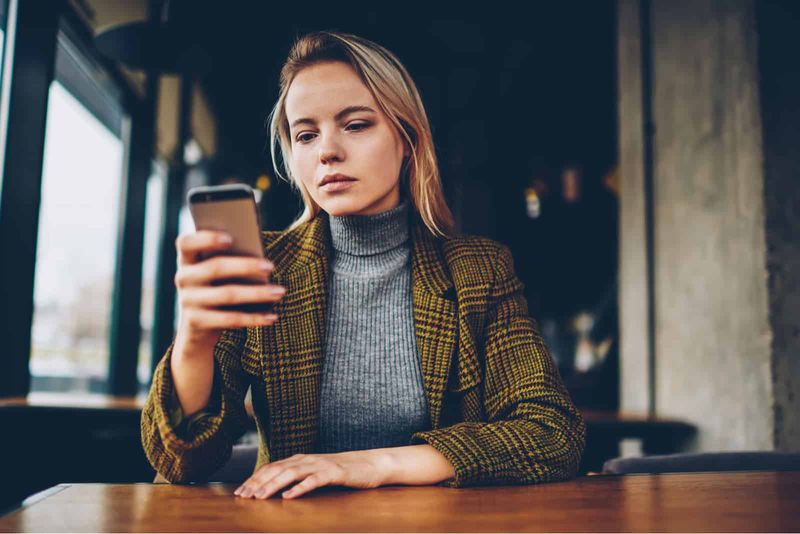 peinzende vrouw op zoek naar haar smartphone