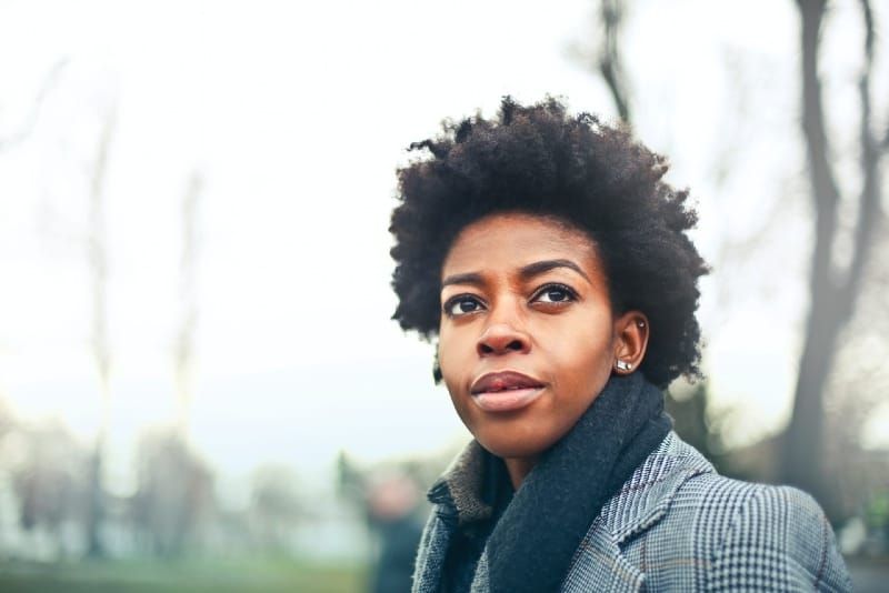 vrouw in grijze jas die buiten staat