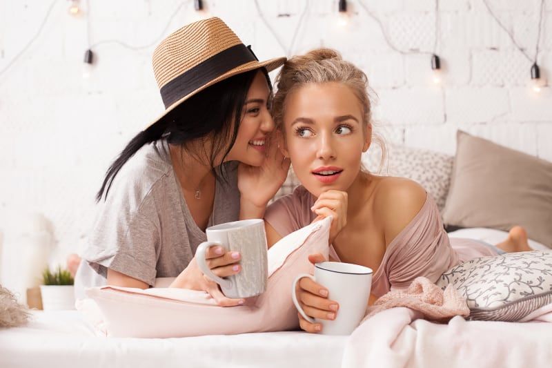 年轻漂亮的女人在家里对她的女性朋友耳语