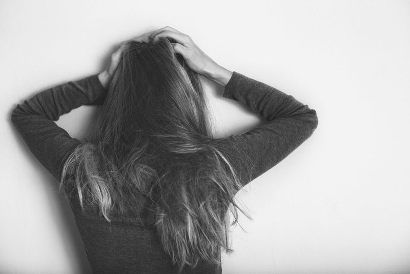 امرأة مكتئبة تقف على الحائط بمفردها ممسكة رأسها في صورة منغم