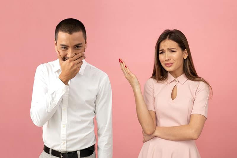 تتضايق المرأة من ضحك الرجل وهو يغطي فمه