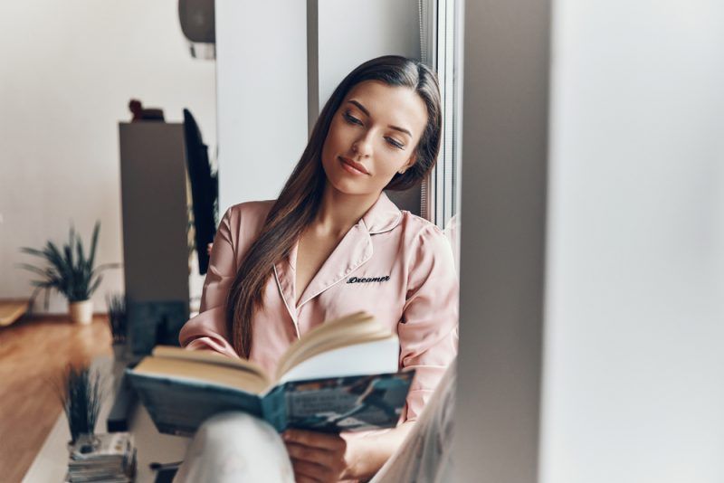magandang brunette na babae na nagbabasa ng libro