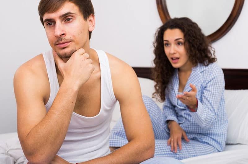 paar streiten sich auf dem bett frau sitzt hinter dem mann