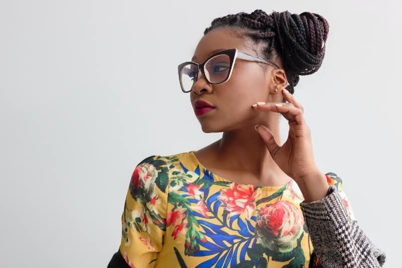 mulher de top floral amarelo em pé perto da parede