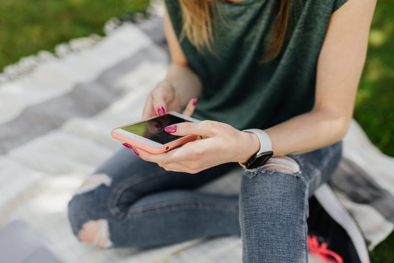 kvinde, der bruger telefonen, mens hun sidder i parken