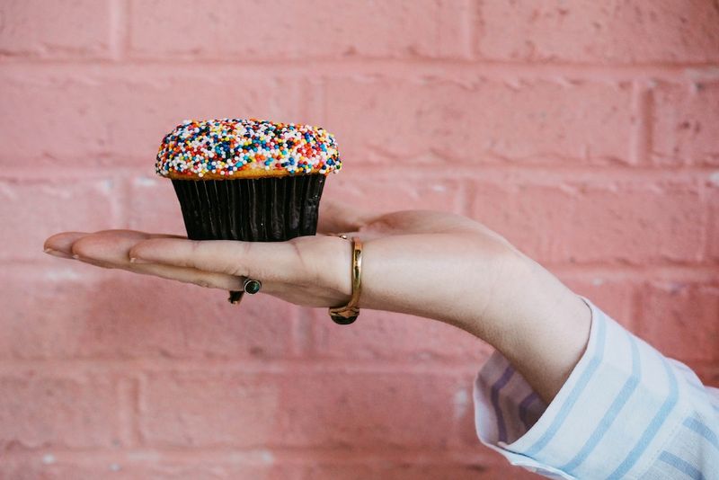 Frau mit Cupcake, während sie in der Nähe der Wand steht