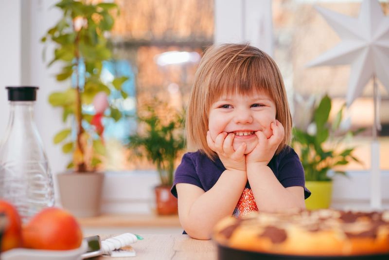 taapero hymyilee istuessaan pöydän ääressä