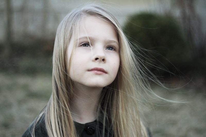 Blondes Mädchen, das aufschaut, während es im Freien steht