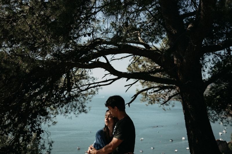 άνδρας και γυναίκα αγκαλιάζονται ενώ στέκονται κοντά στο δέντρο