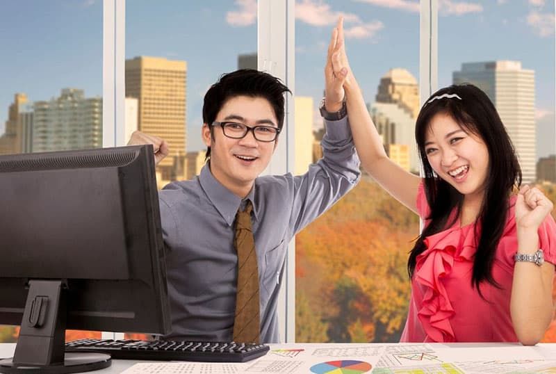 两名亚洲工人在办公室里拍手庆祝