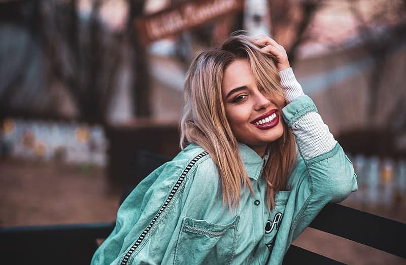 linda mulher sorridente, apoiando-se no banco vestindo jaqueta jeans