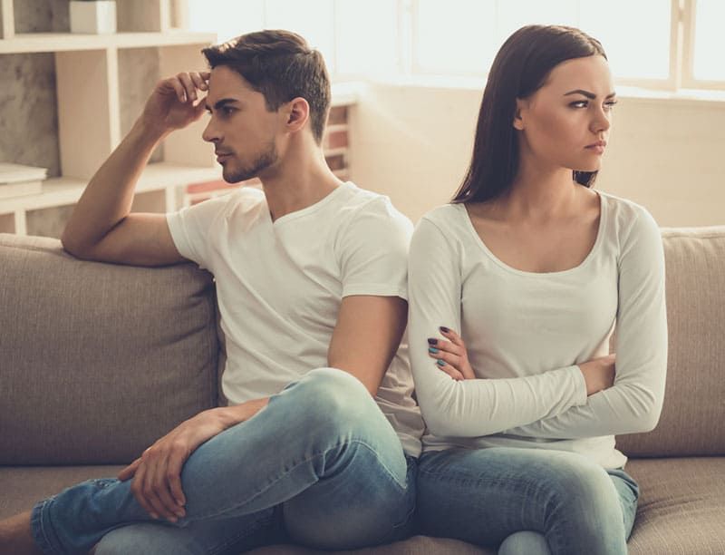 Schönes junges Paar hat einen Streit, während es zu Hause auf dem Sofa sitzt